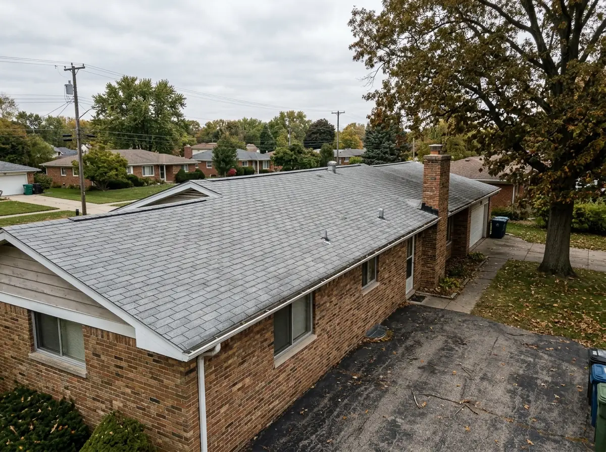 Flat three-tab asphalt shingles in a uniform gray brick-like pattern on a low ranch roof, with the tab cutouts lined up